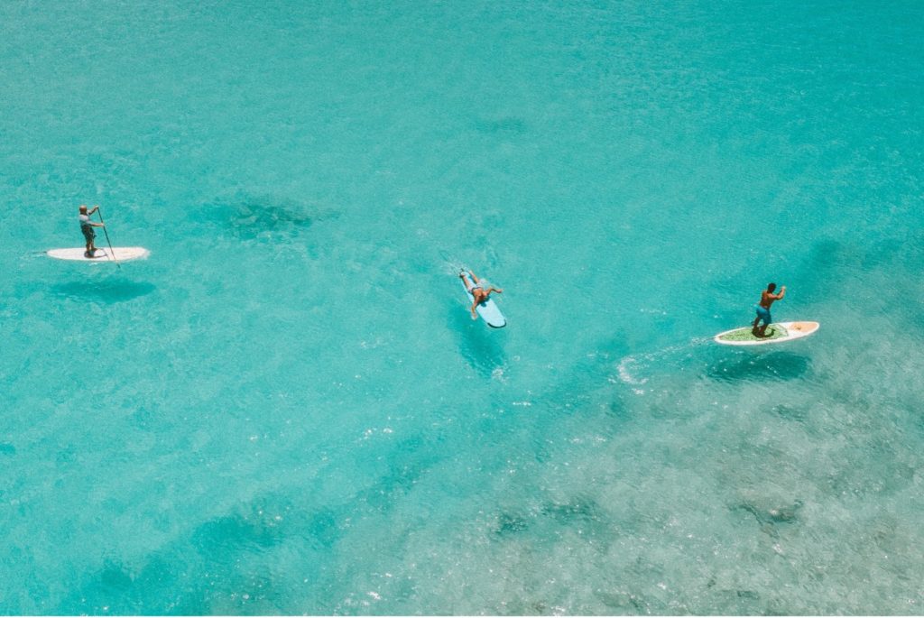 Picture of 3 paddleboarders shot from above as they enjoy the ocean